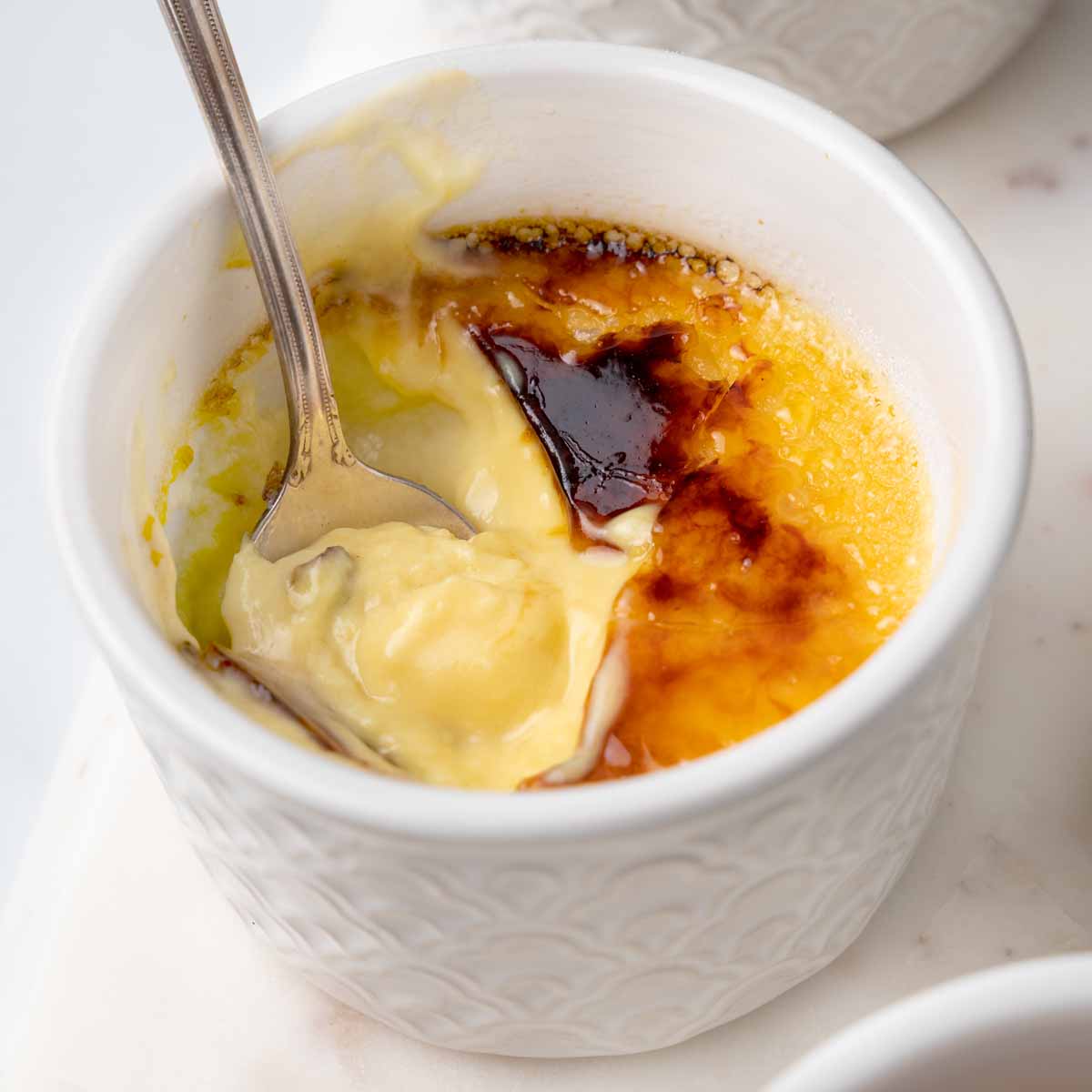 close up of spoon dipped into the creme brulee in the white ramkin