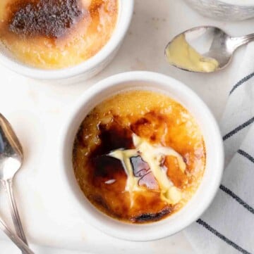 overhead view of 3 cups of creme brulee with one of the sugar tops cracked showing the custard