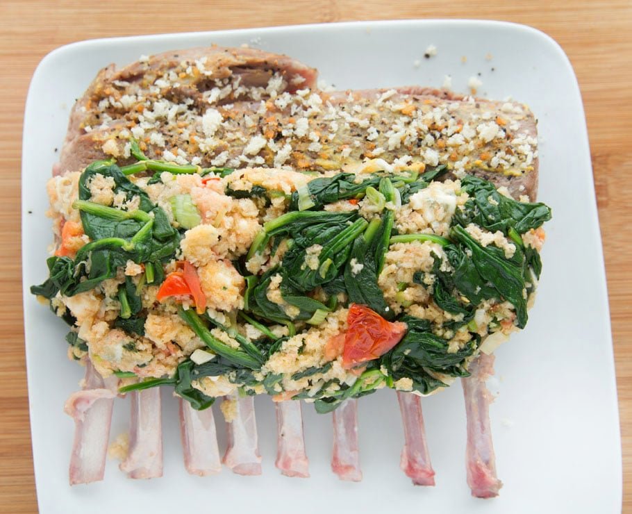 overhead shot of an uncooked stuffed rack of lamb on a white plate