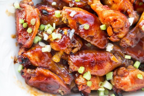  Chinese Sticky wings garnished with sliced scallions on a white plate