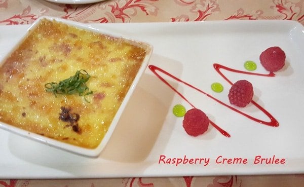 creme brulee with raspberries on a white plate