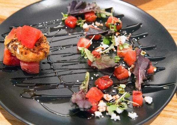 black plate with watermelon goat cheese salad