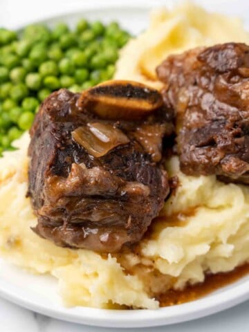 Guinness beef ribs on a bed of mashed potatoes on a white plate