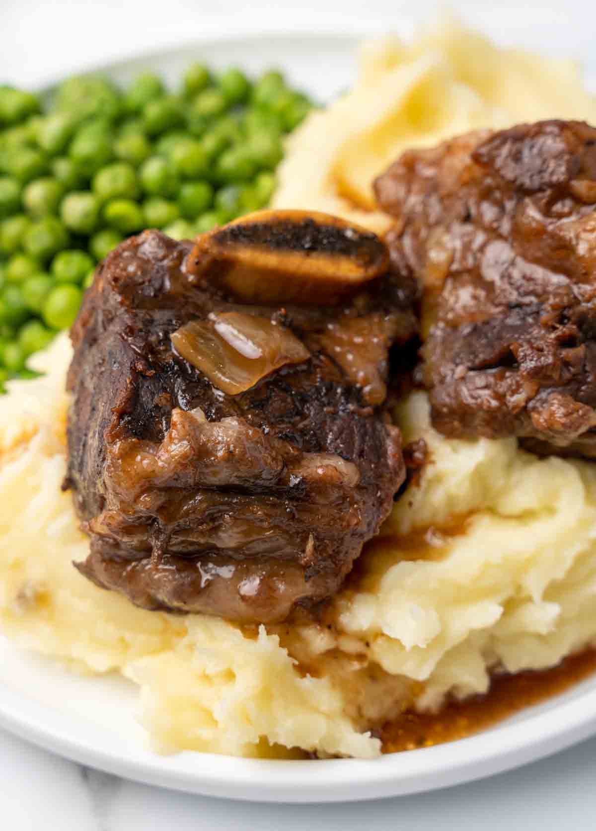 Guinness beef ribs on a bed of mashed potatoes on a white plate