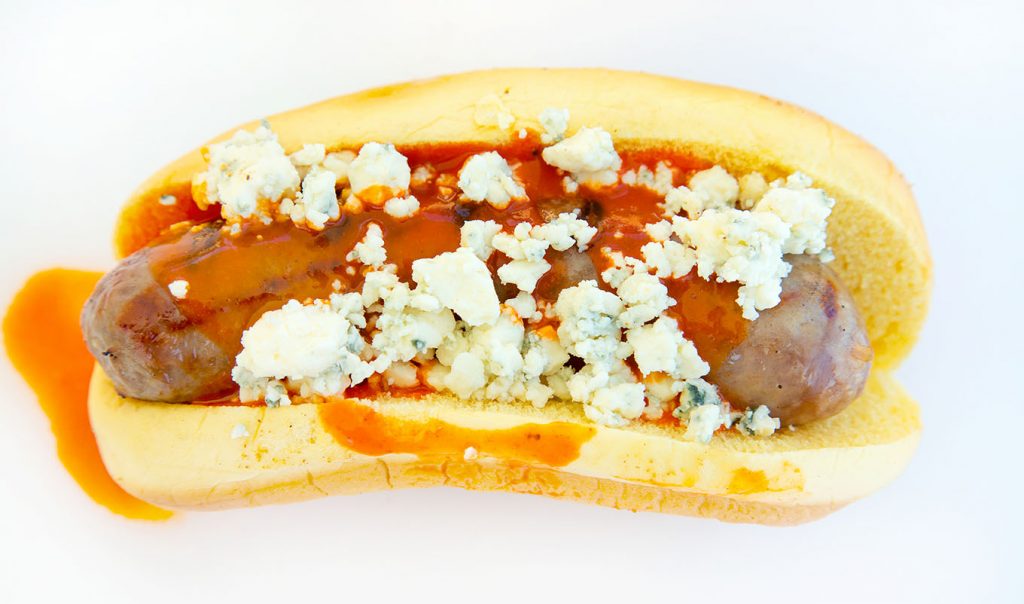 grilled Brat topped with buffalo sauce and bleu cheese