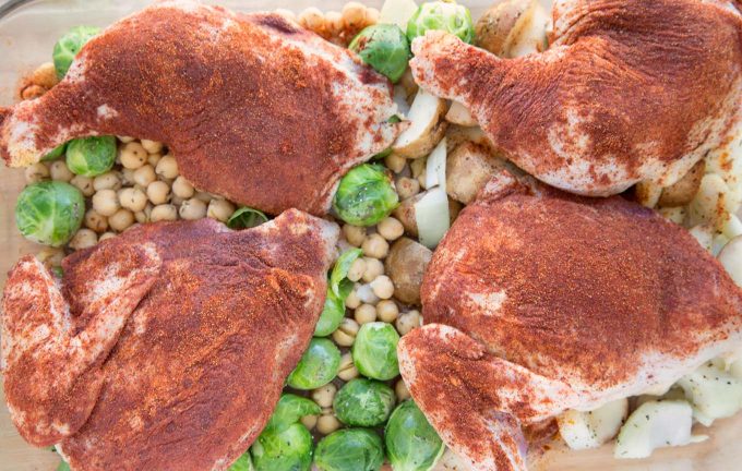 uncooked seasoned Chicken quarters with Brussels Sprouts and Chic Peas in a baking dish