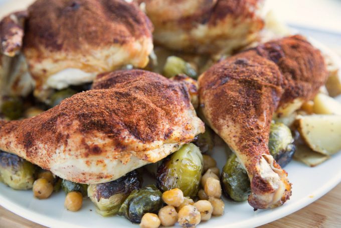 side view of Smoky Roasted Chicken with Brussels Sprouts and Chic Peas on a white platter