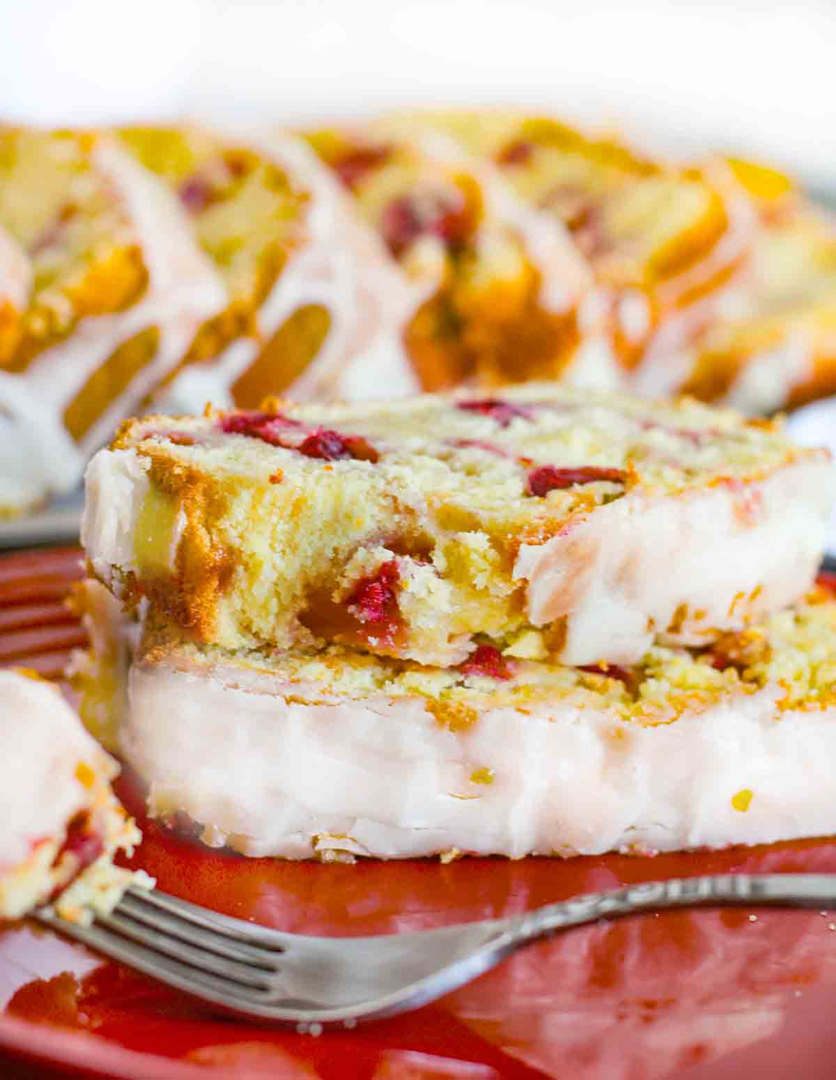 Cranberry orange bread stacked on a red plate with a fork.
