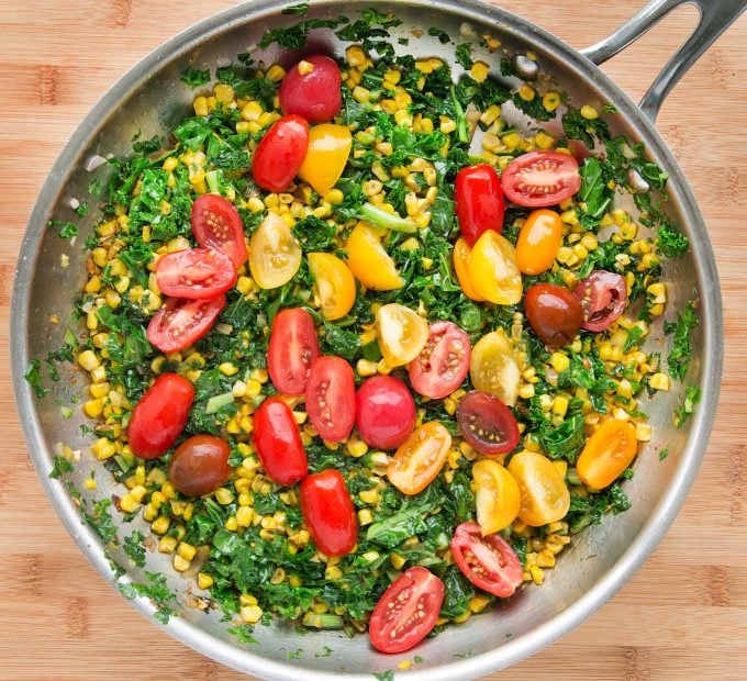 overhead shot of kale and corn succotash with grape tomatoes in a large saute pan