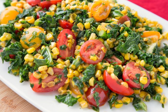 side view of kale and corn succotash with grape tomatoes on a white platter