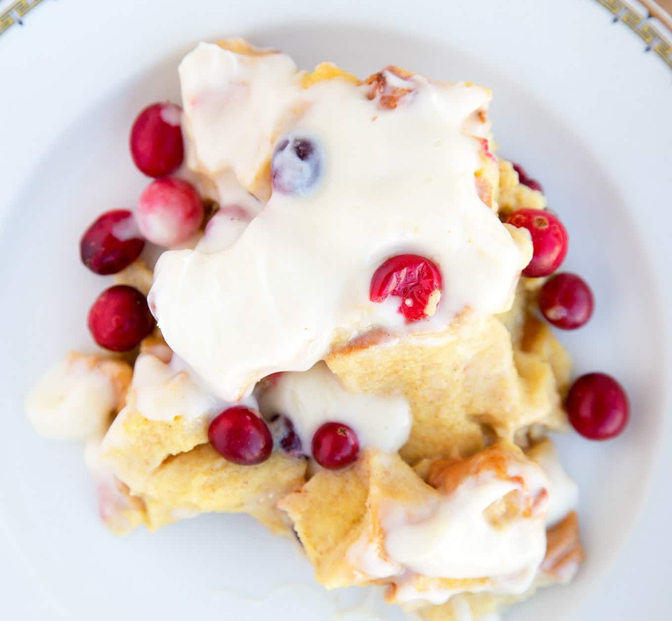 Cranberry Eggnog Bread Pudding with a Bourbon Cream Cheese Frosting on a white plate