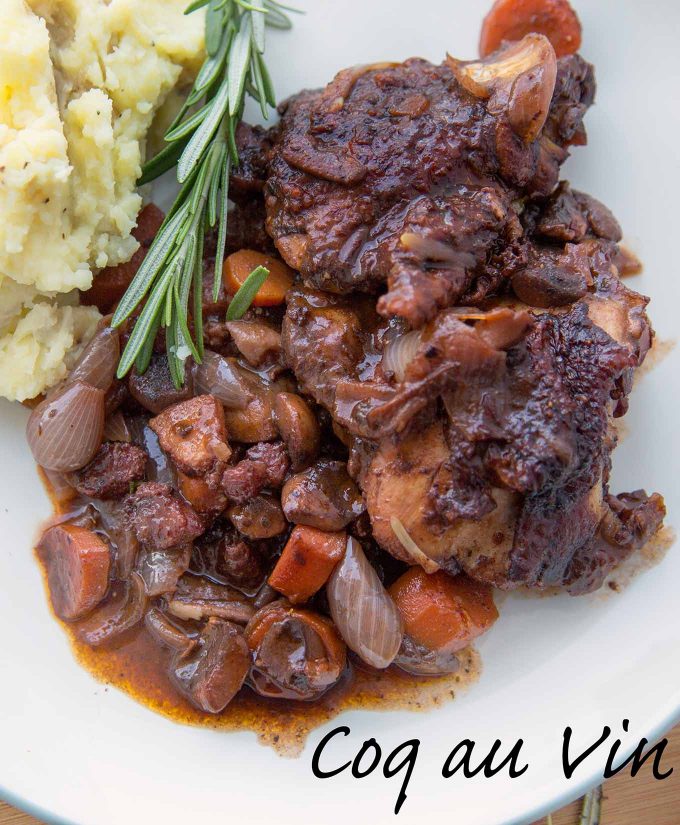 Coq au Vin with a sprig of rosemary and mashed potatoes on a white plate