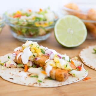 grilled shirmp street taco on cutting board with ingredients in the background