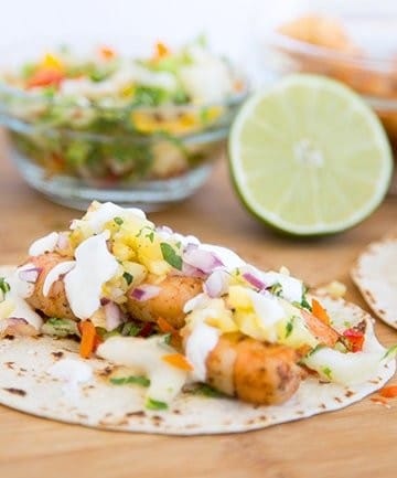 grilled shirmp street taco on cutting board with ingredients in the background