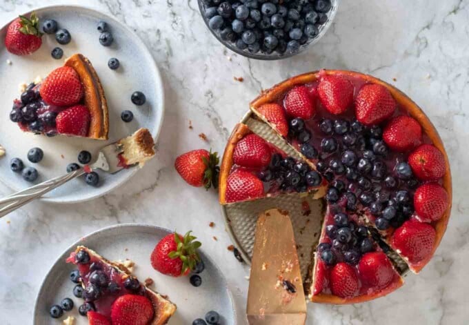 overhead view of sliced cheesecake with slices next to it on plates