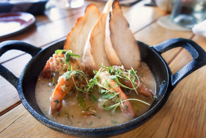 shirmp in a garlic sauce sitting in a small cast iron skillet with slices of toasted bread