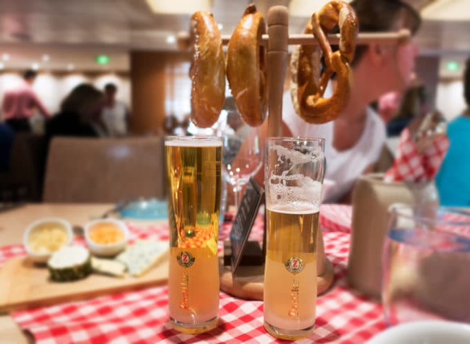 pretzels hanging on a rack with beer in glasses on a red checkered table cloth