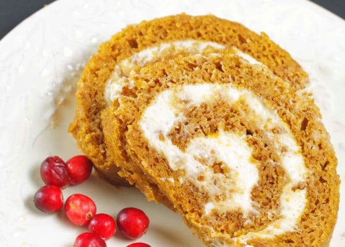 2 slices of pumpkin roll with cranberries on a white plate