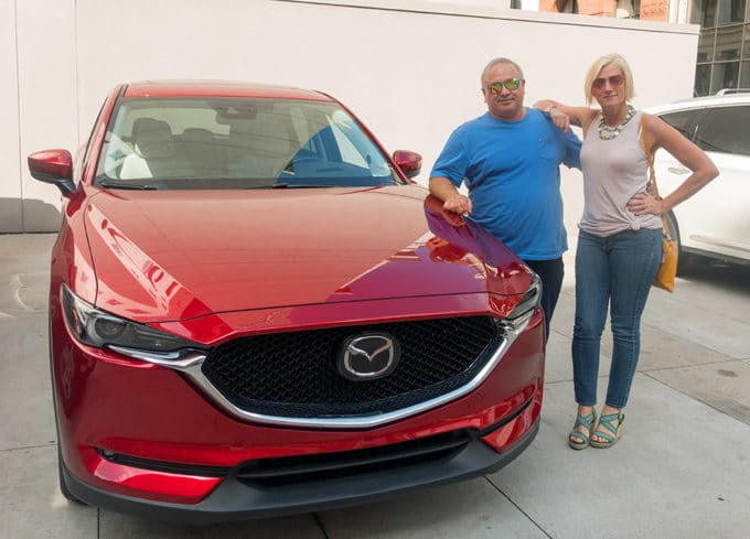 Chef Dennis and Mia Voss next to a Soul REd Mazda CX-5 in a parking lot