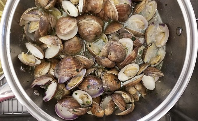 Cooked clams in pot with broth.