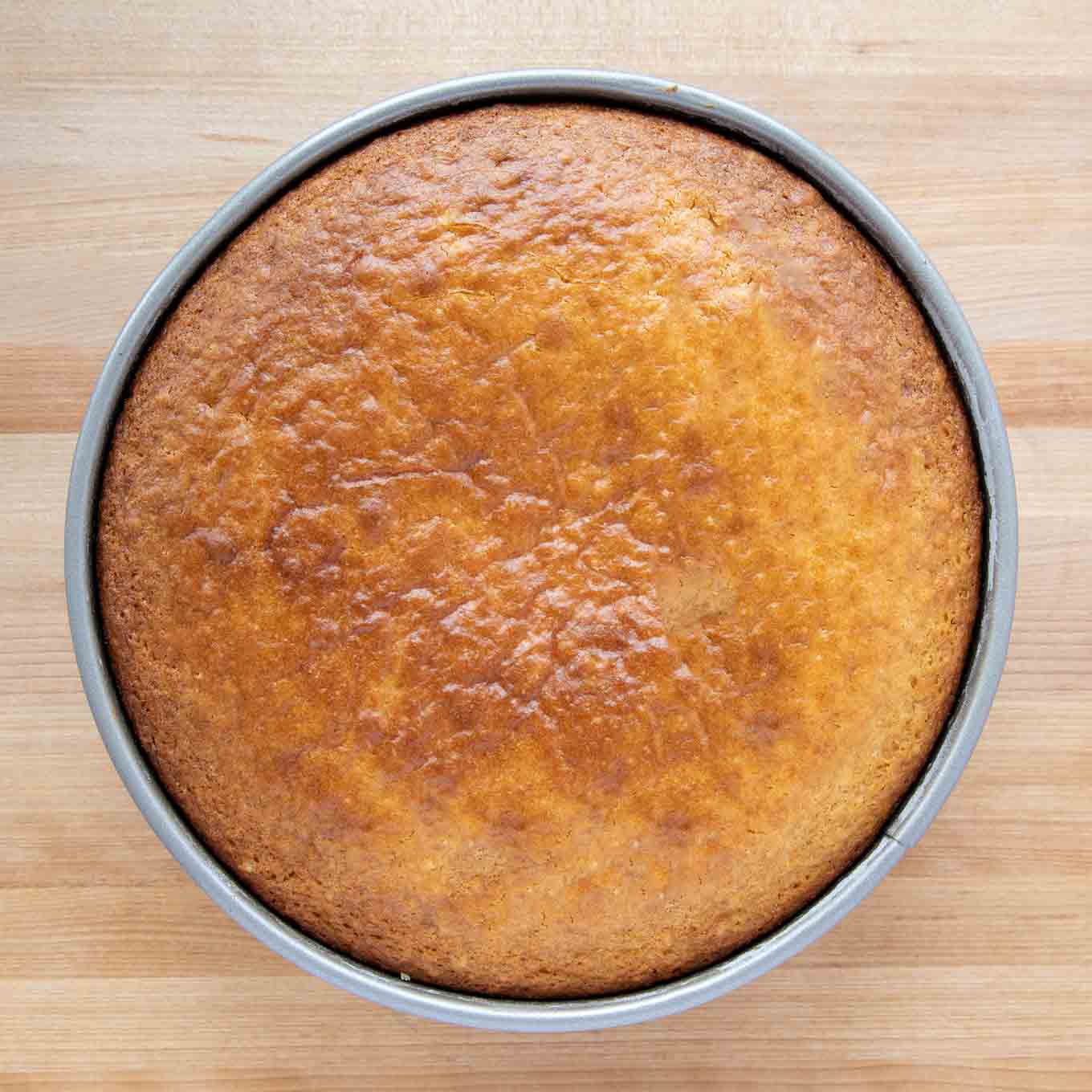 golden brown cake in the pan on a wooden cutting board