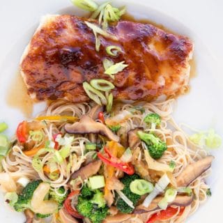 miso glazed cod with stirfried vegetables over noodles on a white plate