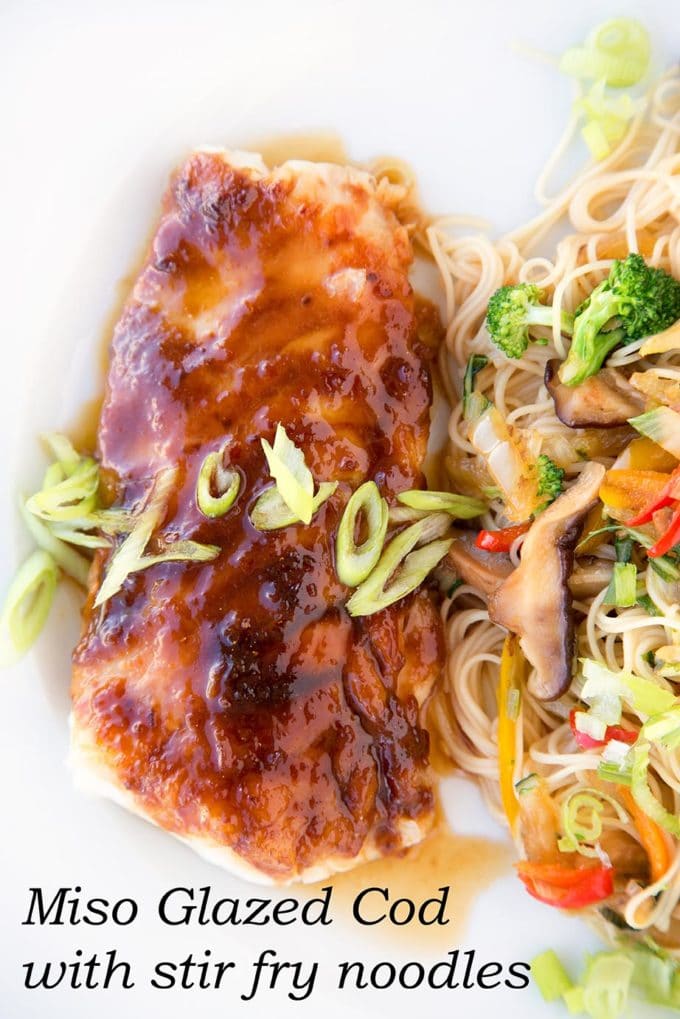 overhead long vertical view of miso glazed cod with stirfried vegetables over noodles on a white plate