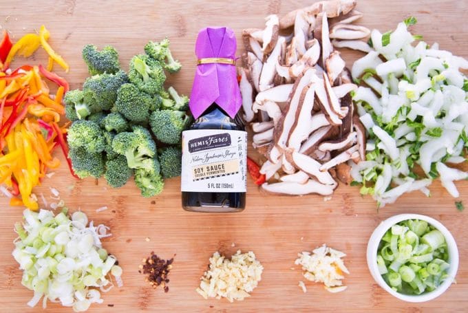 prepped vegetables for stirfry with Hemisfares soy sauce, garlic, ginger and red pepper flakes on a cutting board