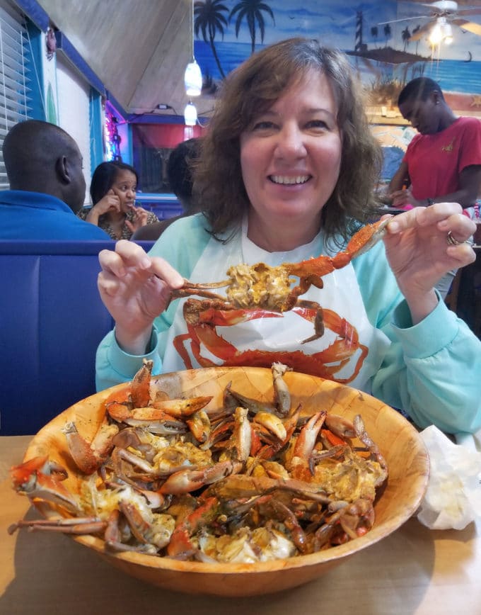 a bowlful of cooked and cleaned crabs with a woman holding up one of the crabs at The Crab Stop in Daytona Beach