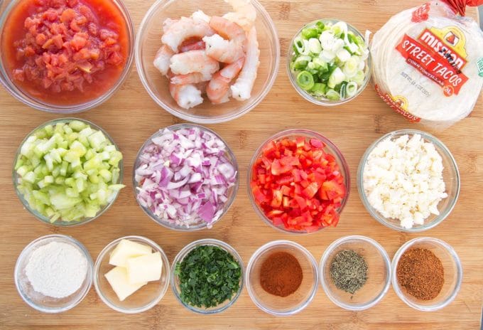 bowls of ingredients to make etouffee street tacos on a wooden cutting board