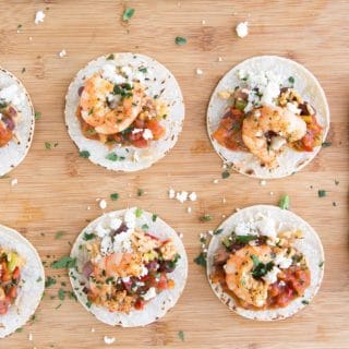 6 etouffee street tacos with a row of corn tortillas on a wooden cutting board