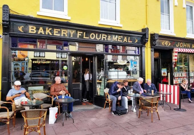 A coffee and pastry shop in Killarney, Ireland with people sitting at tables outside in front of the shop