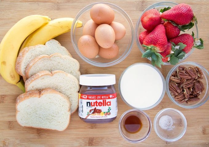 ingredients to make waffle iron banana stuffed french toast with nutella, strawberries and pecans