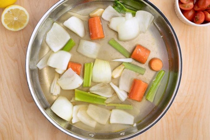 vegetables and court bouillon liquids in a large saute pan