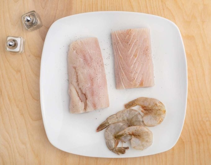 mahi-mani and shrimp with salt and pepper on a white plate