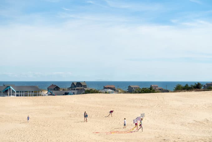 people flying kites on Jockey's Ridge with the bay in the background on the Outer banks