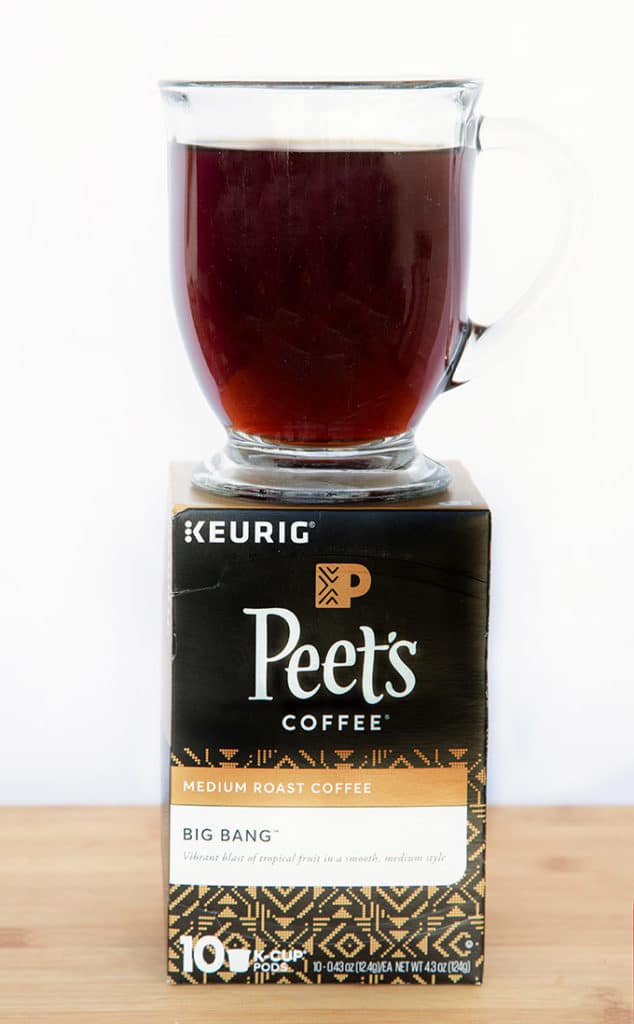 Box of Peet's Coffee K-Cups with a glass mug of black coffee sitting on top of the box