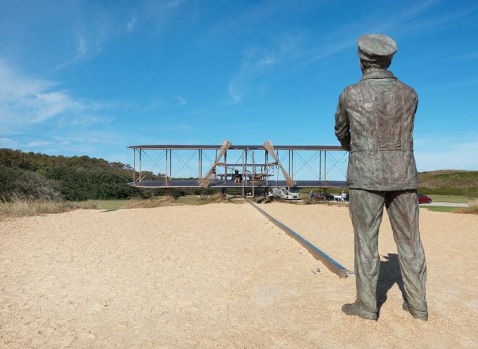 statues of the Wright Brothers and their plane on a sand dune in Kitty Hawk 