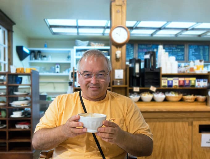 Chef Dennis holding a white bowl of coffee in a coffee shop