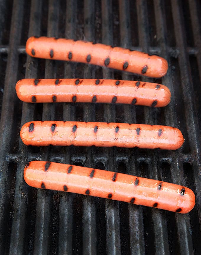 hot dogs with grill marks cooking on a barbecue grill