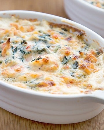 white oval baking dish filled with salmon and spinach dip