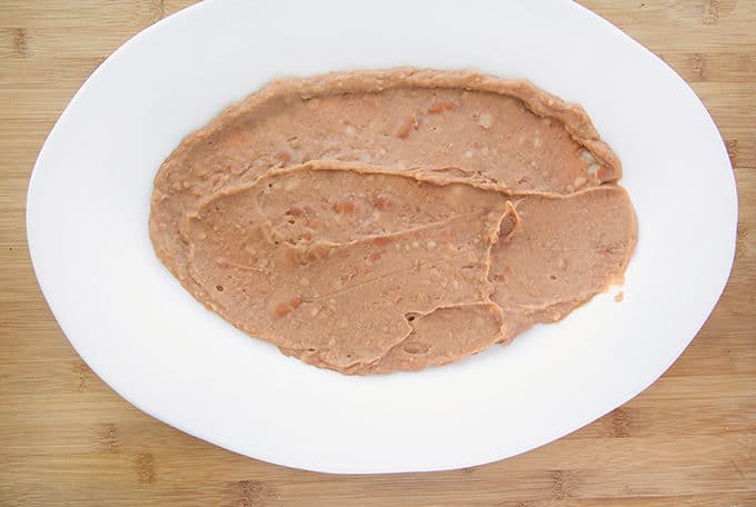 refried beans spread on a large white oval platter