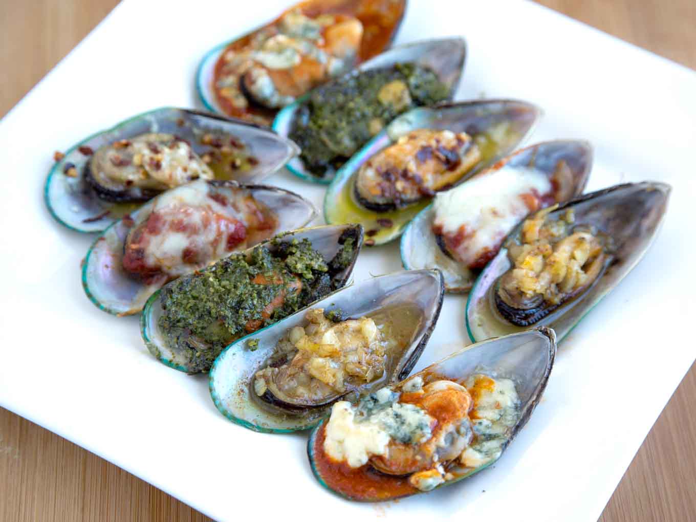 mussels with five different toppings on a white platter