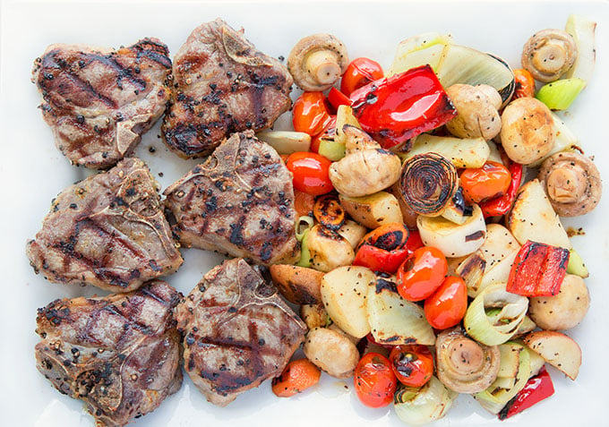 grilled lamb and grilled vegetables on a white plater