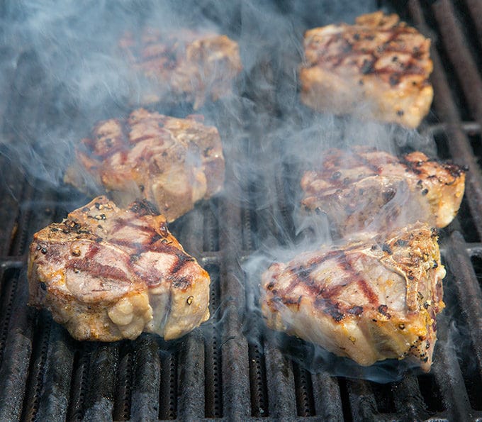 lamb chops on a grill with smoke coming off of them