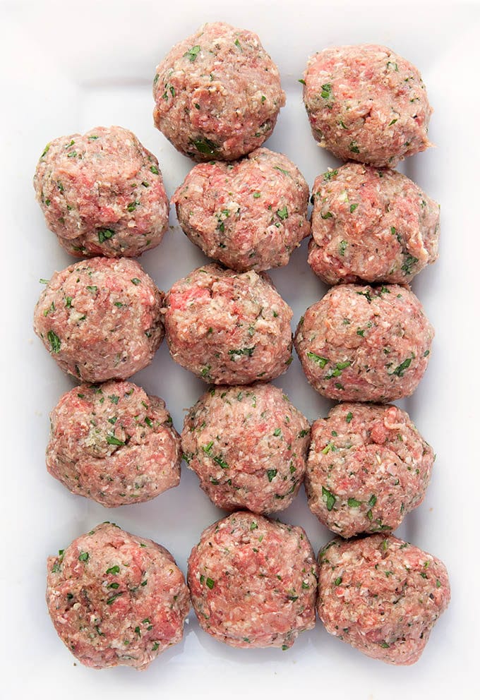 raw meatballs place in rows on a rectangular white serving dish