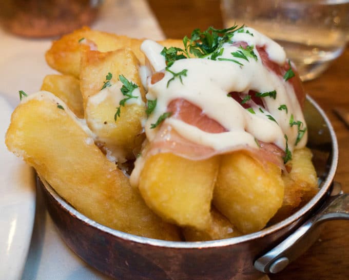 Hand cut chips with truffled goats cheese, ventreche bacon and lardo crudo served in a stainless steel bowl at Fade Street Social in Dublin Ireland