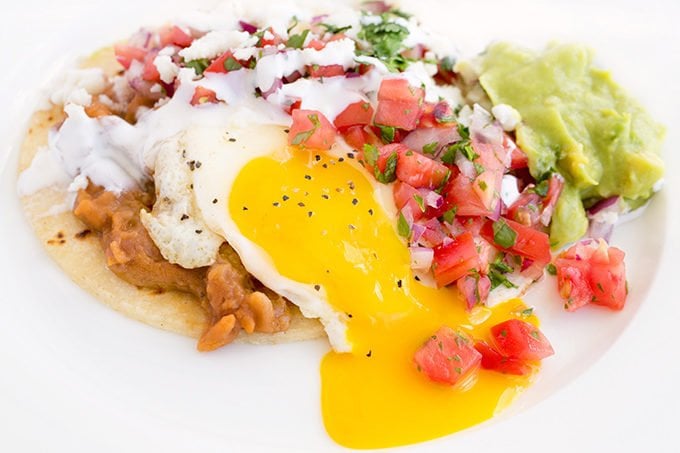 Huevos Rancheros with yolk running on a white plate.