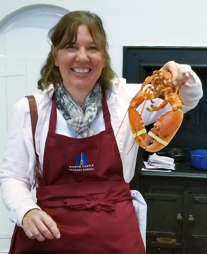 Lisa (from AskChefDennis.com) holding a lobster at the Howth Castle Cookery School