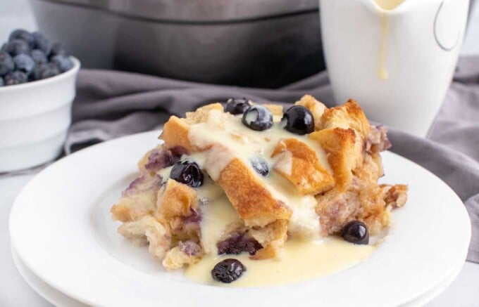 blueberry bread pudding on a white plate with creme anglais